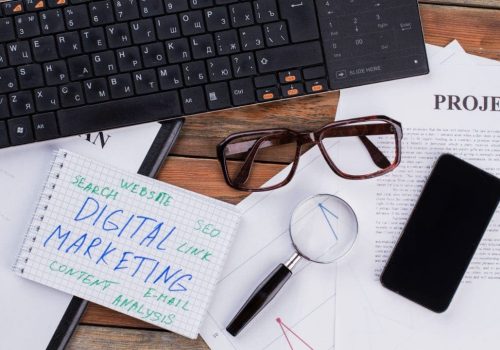 Digital marketing and other information written on papers and a laptop.